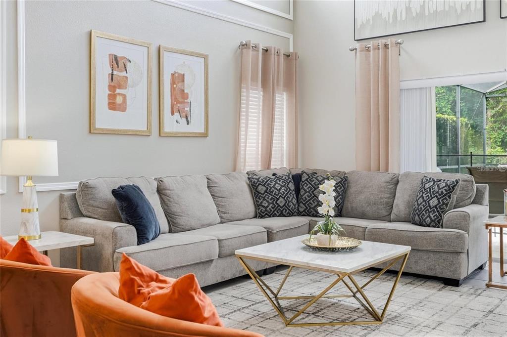 A living room features a grey sectional sofa, a marble coffee table, and orange accent chairs — 8426 SECRET KEY COVE, KISSIMMEE, FL