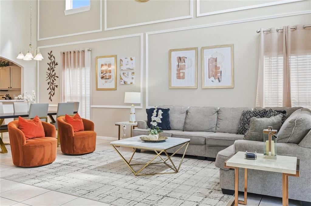A living room features a grey sectional sofa, two orange armchairs, and a marble coffee table — 8426 SECRET KEY COVE, KISSIMMEE, FL