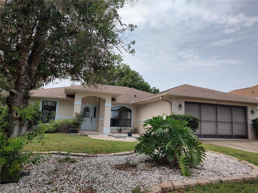 A single-story house with a beige exterior, a two-car garage, and a landscaped front yard — 3716 E COVE PARK TRAIL, HERNANDO, FL