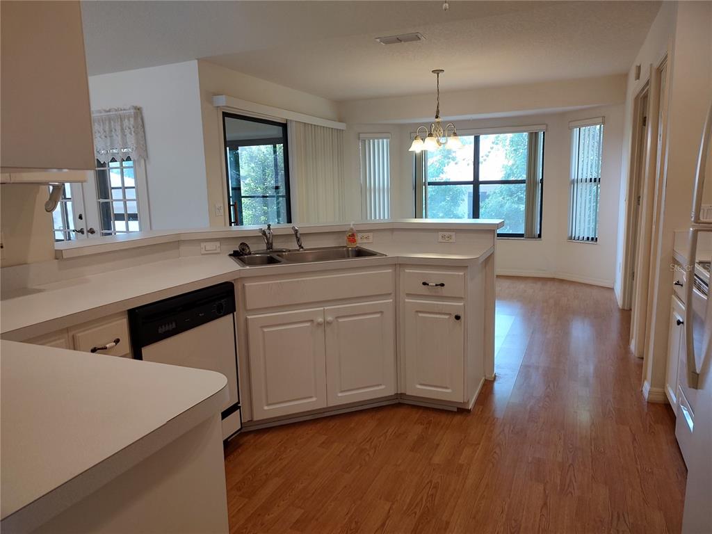 A kitchen with white cabinets, a double sink, and wood flooring overlooks a dining area — 3716 E COVE PARK TRAIL, HERNANDO, FL