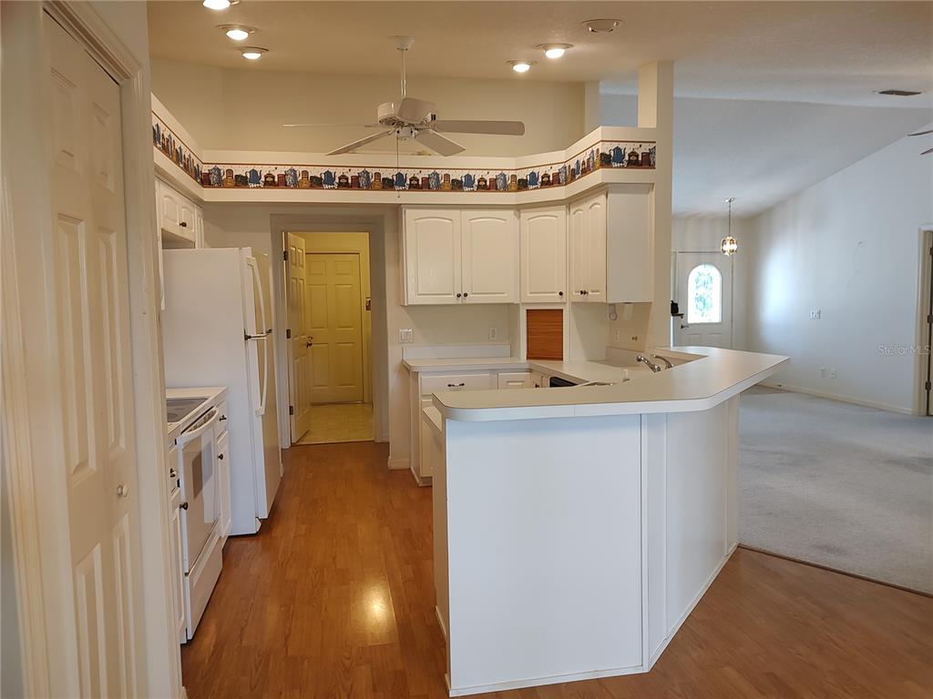 A kitchen with white cabinets, wood flooring, and a breakfast bar overlooking a living area — 3716 E COVE PARK TRAIL, HERNANDO, FL