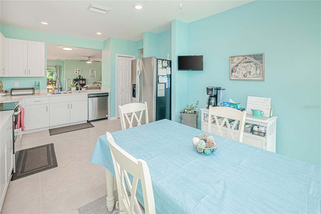 A kitchen and dining area with light blue walls, white cabinets, and a blue tablecloth — 25292 E LENOX CIRCLE, PUNTA GORDA, FL