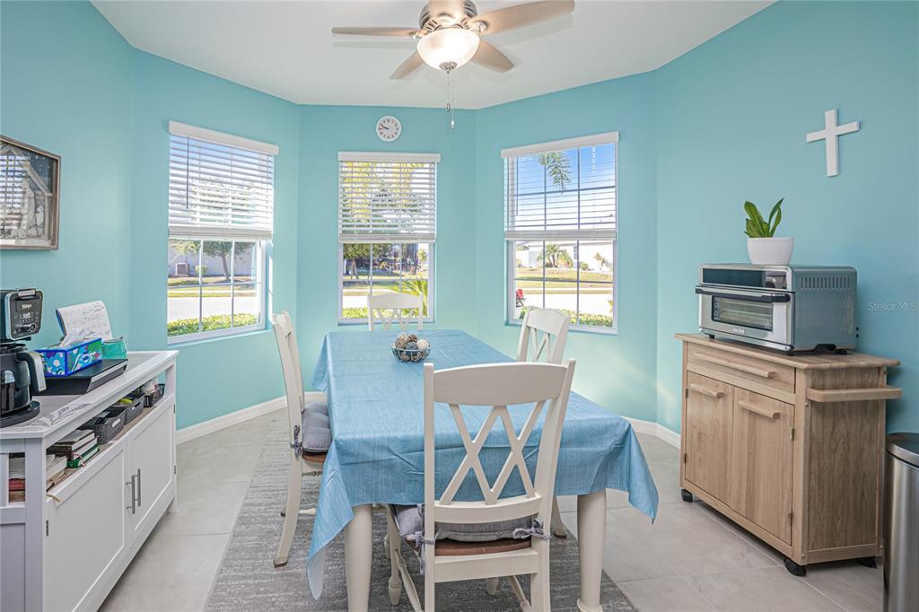 A dining room with light blue walls, a table, chairs, and three windows — 25292 E LENOX CIRCLE, PUNTA GORDA, FL