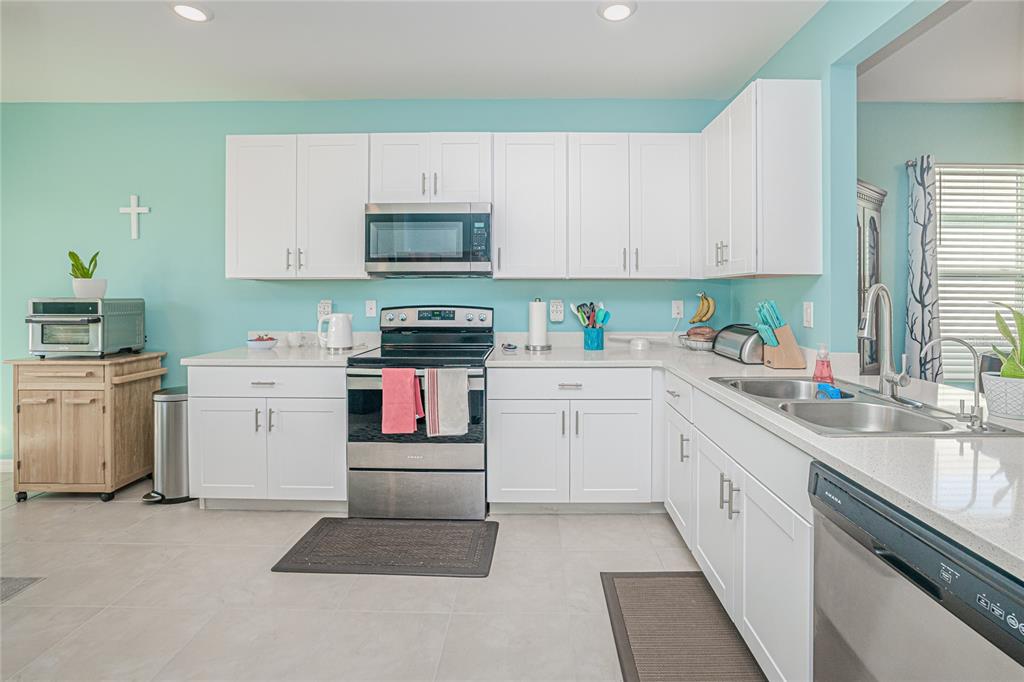 A kitchen features white cabinets, stainless steel appliances, and light blue walls — 25292 E LENOX CIRCLE, PUNTA GORDA, FL