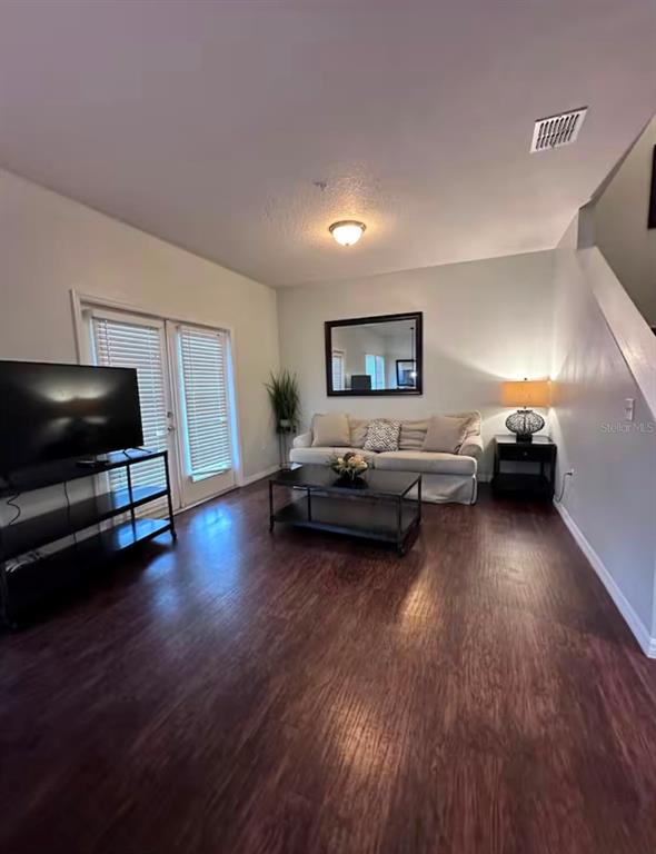 A living room features dark wood-look flooring, a beige sofa, a coffee table, and a television — 5364 DIPLOMAT COURT UNIT 108, KISSIMMEE, FL