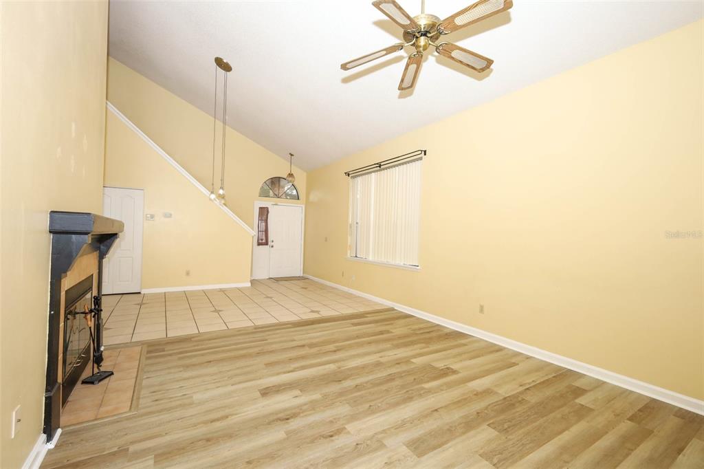 A living room with light wood flooring, a fireplace, and a vaulted ceiling with a fan — 5405 RUTLAND COURT, ORLANDO, FL
