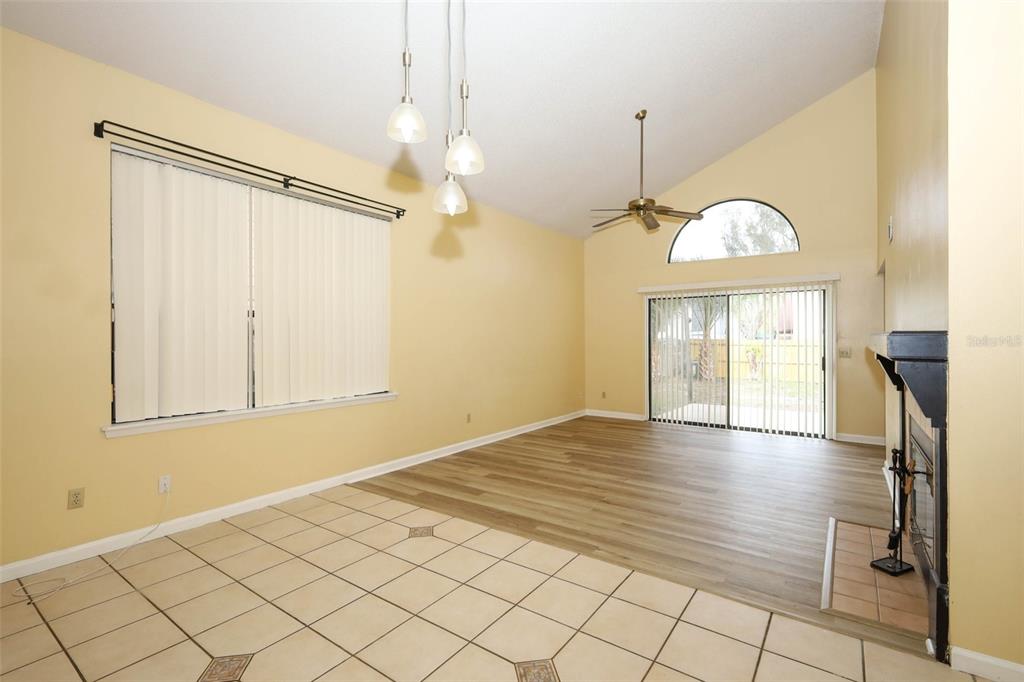 An open living area features tile flooring, wood-look laminate, a vaulted ceiling, and a fireplace — 5405 RUTLAND COURT, ORLANDO, FL