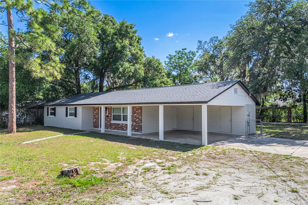 A single-story house with a carport, brick accents, and a gray roof sits on a lot — 2201 CAMELLIA DRIVE, LONGWOOD, FL