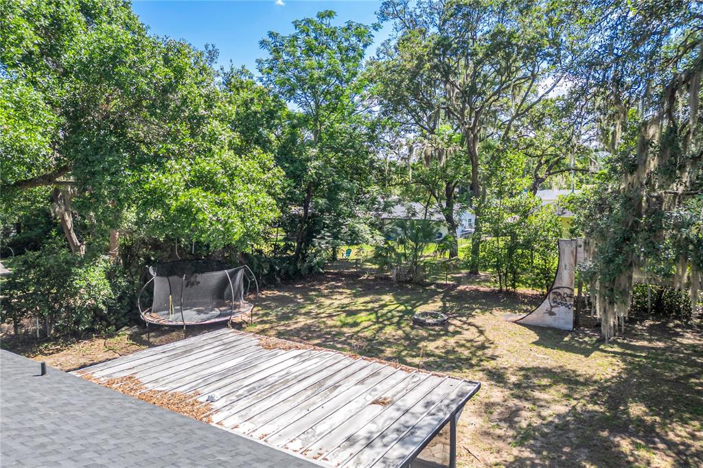 A backyard features a trampoline, a skate ramp, and a metal-roofed patio structure — 2201 CAMELLIA DRIVE, LONGWOOD, FL