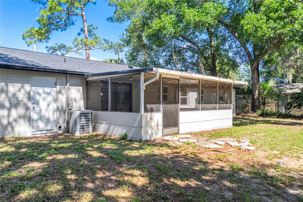 The exterior of a house features a screened-in porch, a white door, and an AC unit — 2201 CAMELLIA DRIVE, LONGWOOD, FL