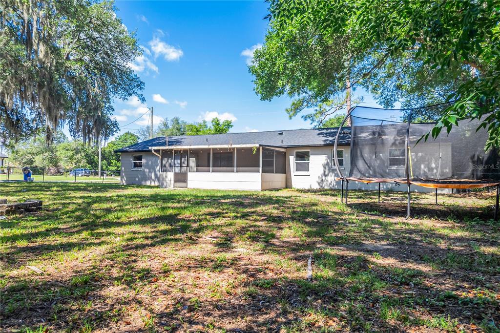 The backyard of a house features a screened-in porch and a large trampoline — 2201 CAMELLIA DRIVE, LONGWOOD, FL