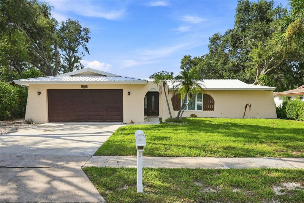 A single-story house with a beige exterior, a brown garage door, and a front lawn — 13344 88TH AVENUE, SEMINOLE, FL