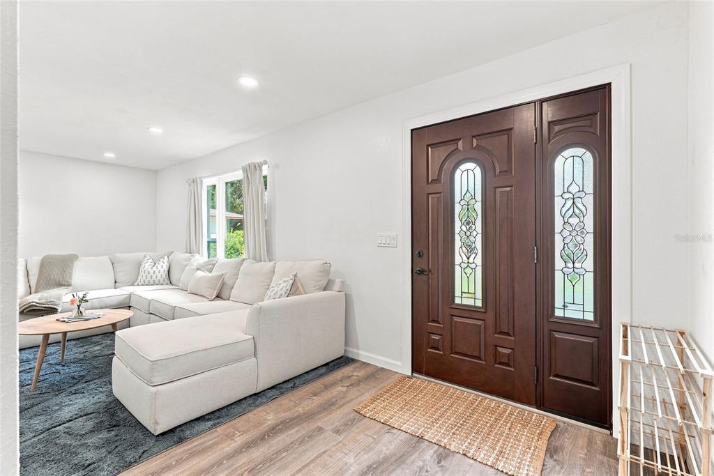 A living room features a white sectional sofa, a wooden coffee table, and a dark door — 13344 88TH AVENUE, SEMINOLE, FL