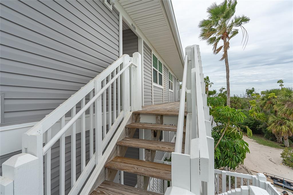 An exterior view of a raised house with wooden stairs leading to a deck entrance — 7201 RUM BAY DR UNIT 4122A, PLACIDA, FL