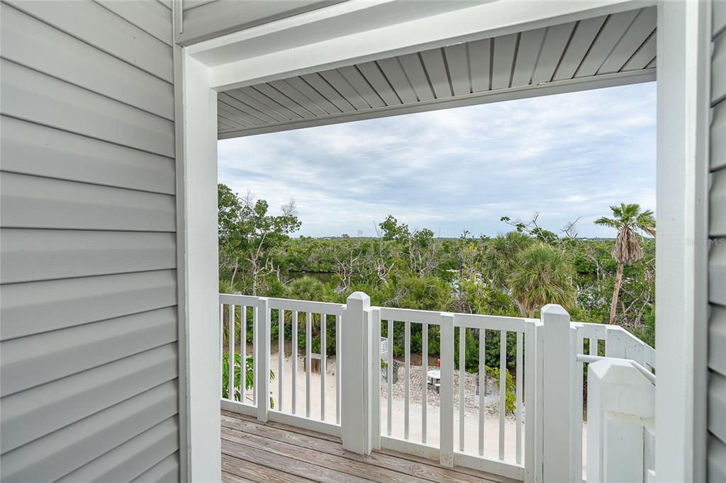 A wooden balcony with a white railing overlooks a wooded area and a small waterway — 7201 RUM BAY DR UNIT 4122A, PLACIDA, FL