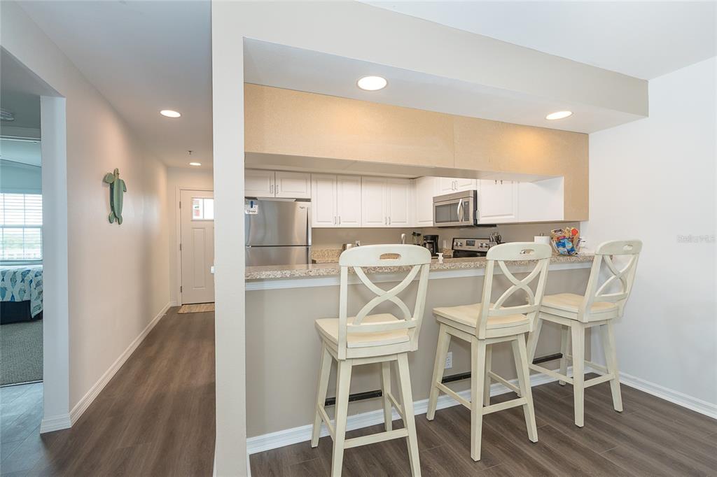 A kitchen with white cabinets and stainless steel appliances features a breakfast bar with stools — 7201 RUM BAY DR UNIT 4122A, PLACIDA, FL