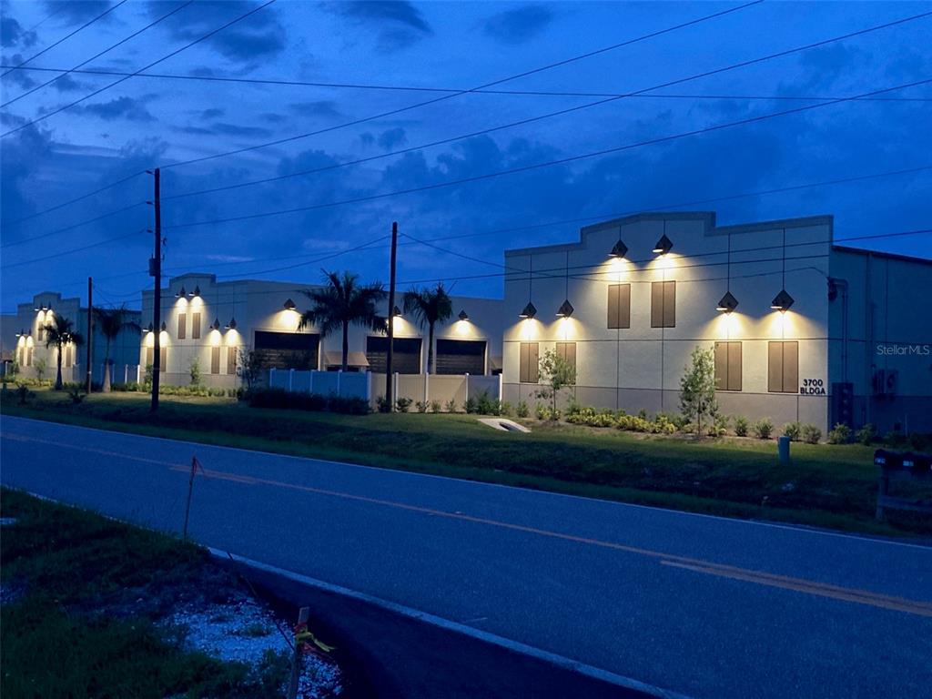 An exterior view of a commercial building complex at dusk with illuminated wall-mounted lights — 5225 TAYLOR ROAD UNIT A9, PUNTA GORDA, FL