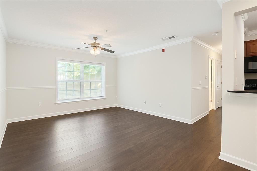 An empty room with dark wood flooring, white walls, a ceiling fan, and a window — 2059 DIXIE BELLE DR UNIT 2059n, ORLANDO, FL