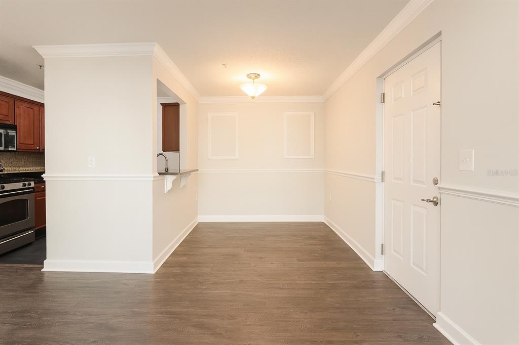 A dining area with wood-look flooring, white walls, chair rail molding, and a pass-through window — 2059 DIXIE BELLE DR UNIT 2059n, ORLANDO, FL