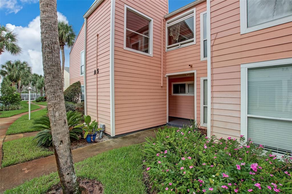The exterior of a peach-colored multi-story building features a unit labeled A5 and landscaping — 6300 S A1A UNIT A5 1U, ST AUGUSTINE, FL