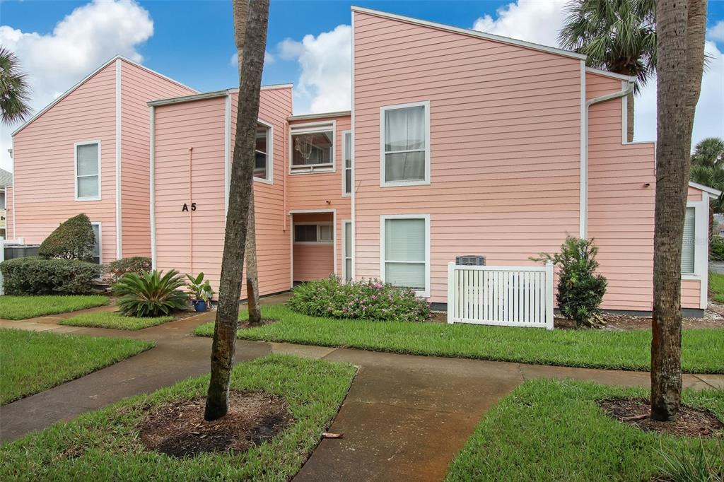 A two-story pink building with horizontal siding and a white fence in the front yard — 6300 S A1A UNIT A5 1U, ST AUGUSTINE, FL