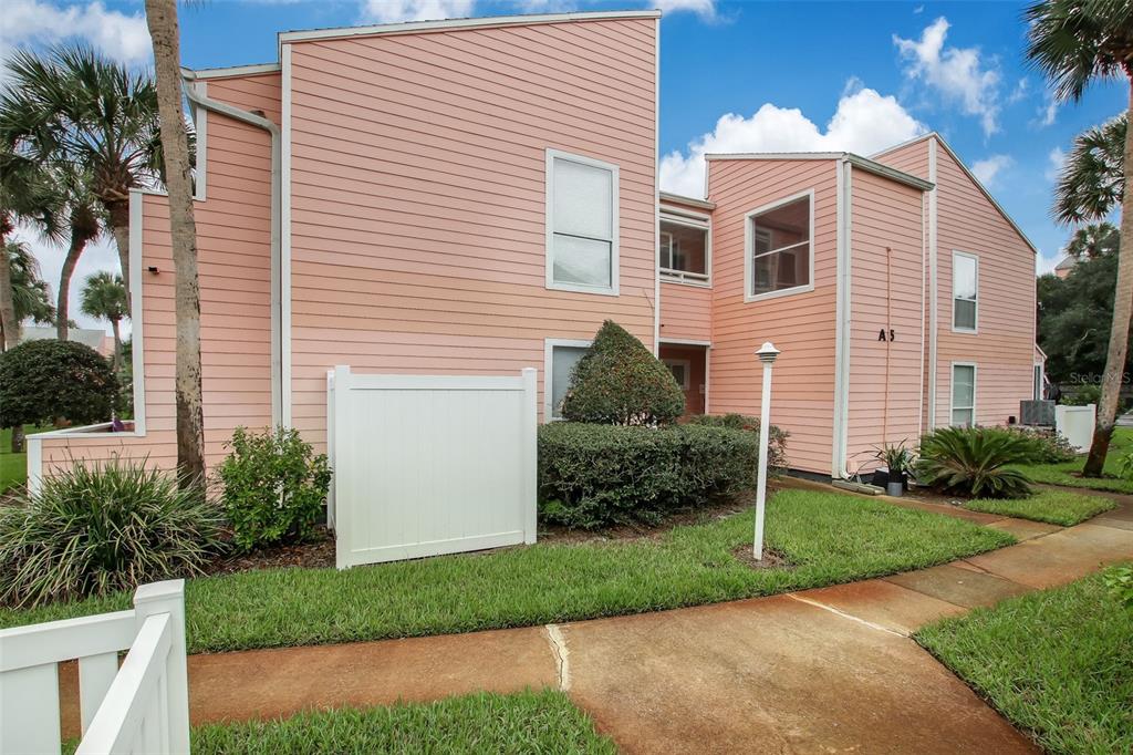 A two-story peach-colored building with horizontal siding and a white privacy fence — 6300 S A1A UNIT A5 1U, ST AUGUSTINE, FL