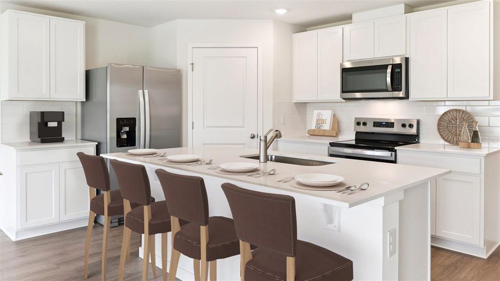 A modern kitchen features white cabinets, stainless steel appliances, and a large central island — 3080 PIGEON COVE STREET, DELTONA, FL