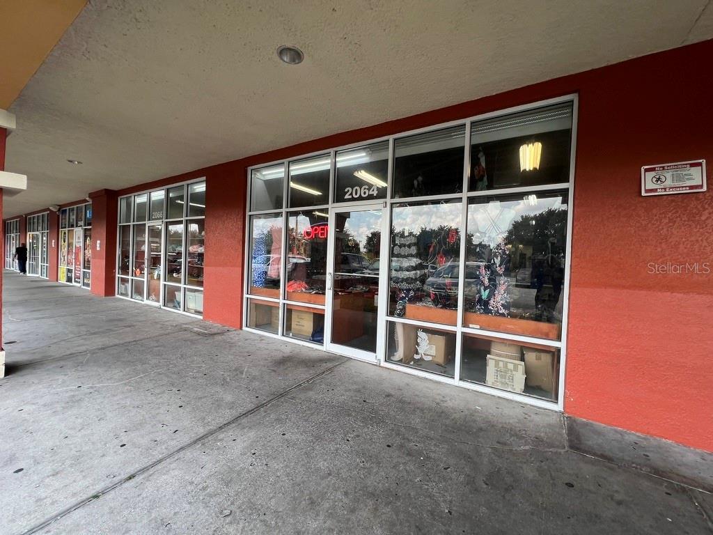 The exterior of a retail storefront features large glass windows and a red painted wall — 2066 E OSCEOLA PARKWAY, KISSIMMEE, FL