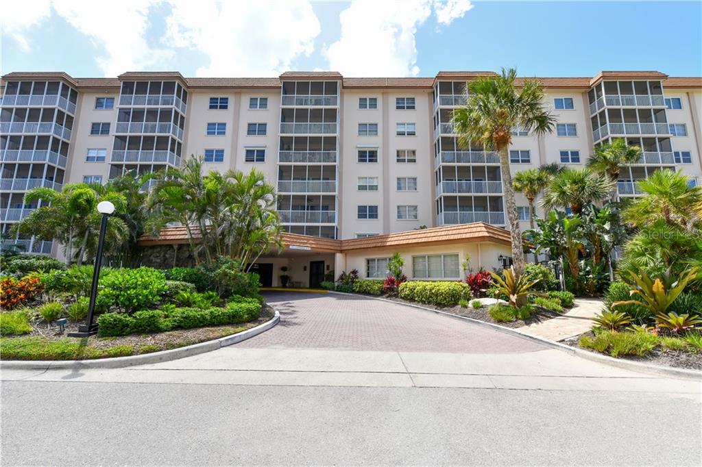 A multi-story apartment building features a paved driveway leading to a covered entrance — 800 BENJAMIN FRANKLIN DRIVE UNIT 403, SARASOTA, FL