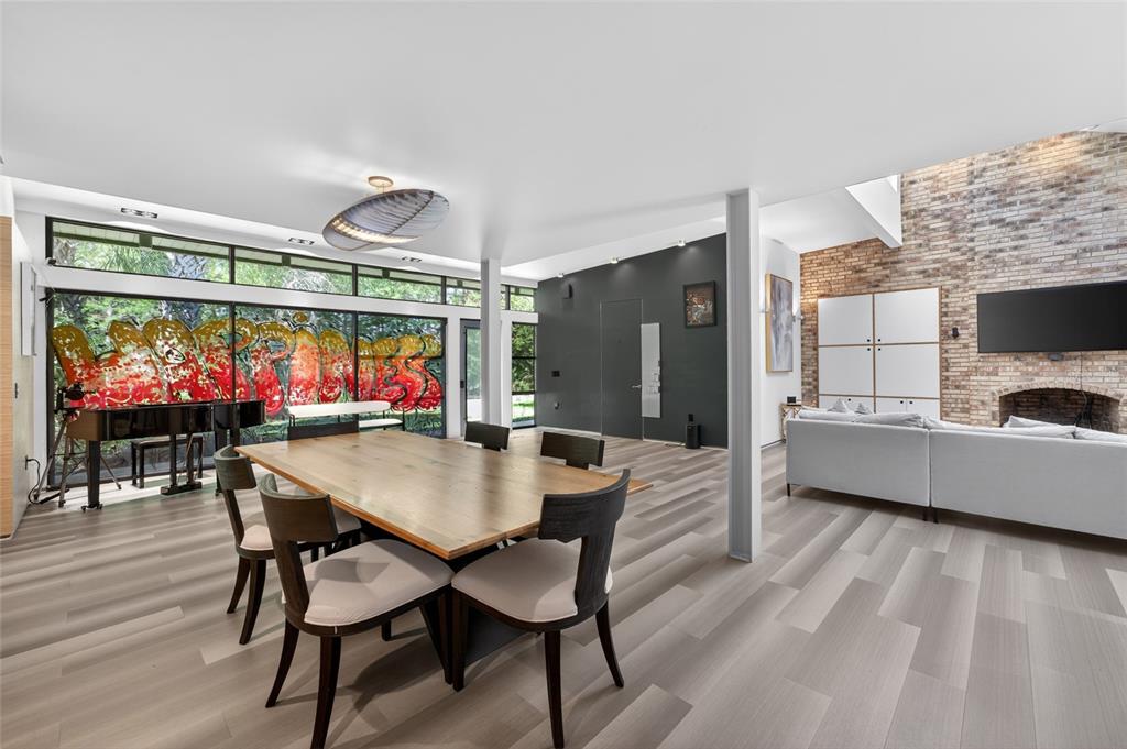 A dining area with a wooden table and chairs sits before floor-to-ceiling graffiti-covered windows — 5425 SADDLEBROOK WAY, WESLEY CHAPEL, FL
