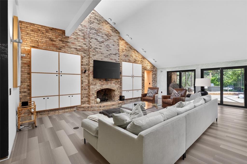 A living room features a brick fireplace, built-in white cabinets, and a large sectional sofa — 5425 SADDLEBROOK WAY, WESLEY CHAPEL, FL