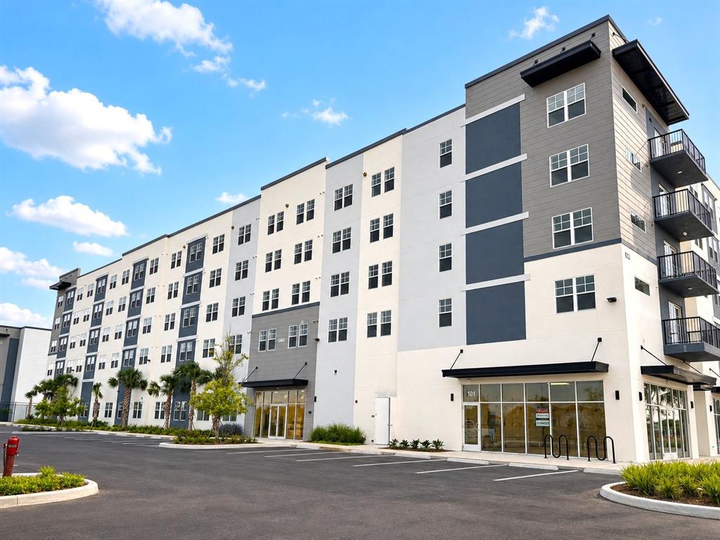 A multi-story apartment building with a parking lot and ground-floor commercial space — 5563 MILLENIA PARK BOULEVARD UNIT 322, ORLANDO, FL