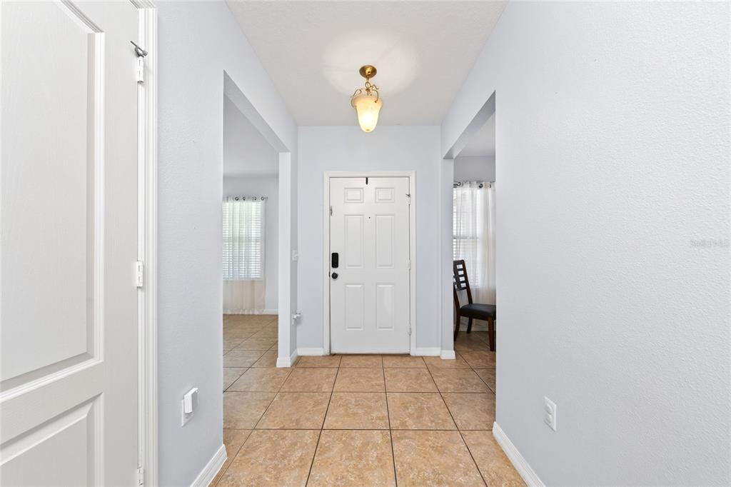 A tiled entryway features a white front door, light blue walls, and a ceiling light — 5590 SILVER THISTLE LANE, ST CLOUD, FL