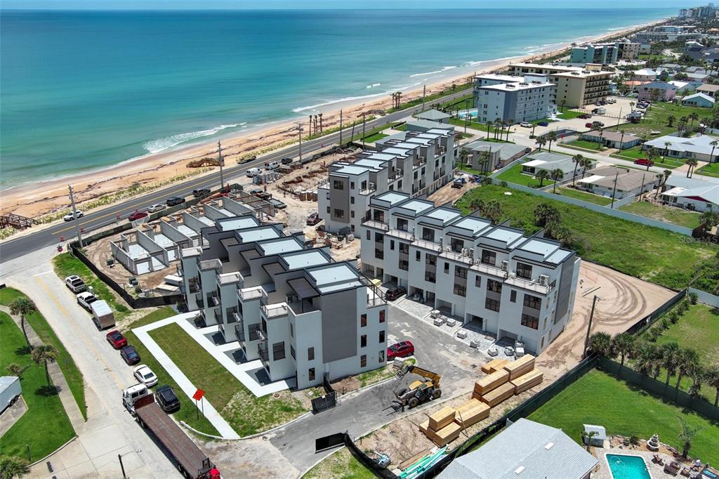 An aerial view shows a coastal construction site with modern townhomes near the ocean — 2360 OCEAN SHORE BOULEVARD UNIT 203, ORMOND BEACH, FL