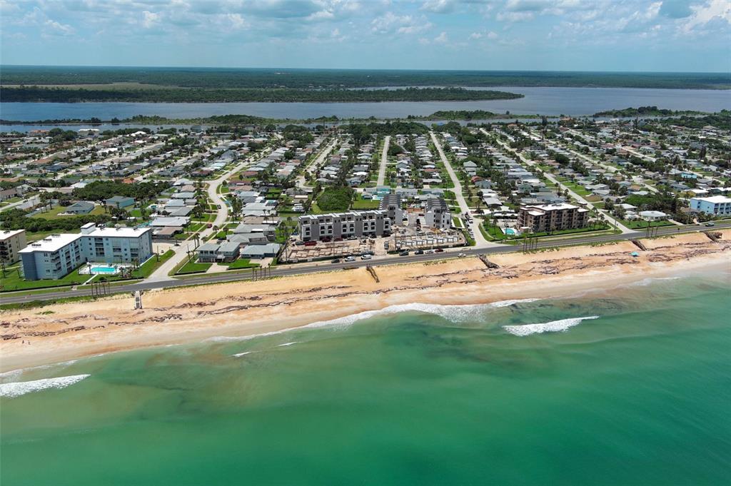 An aerial view shows a coastal neighborhood with a beach, ocean, and a construction site — 2360 OCEAN SHORE BOULEVARD UNIT 203, ORMOND BEACH, FL