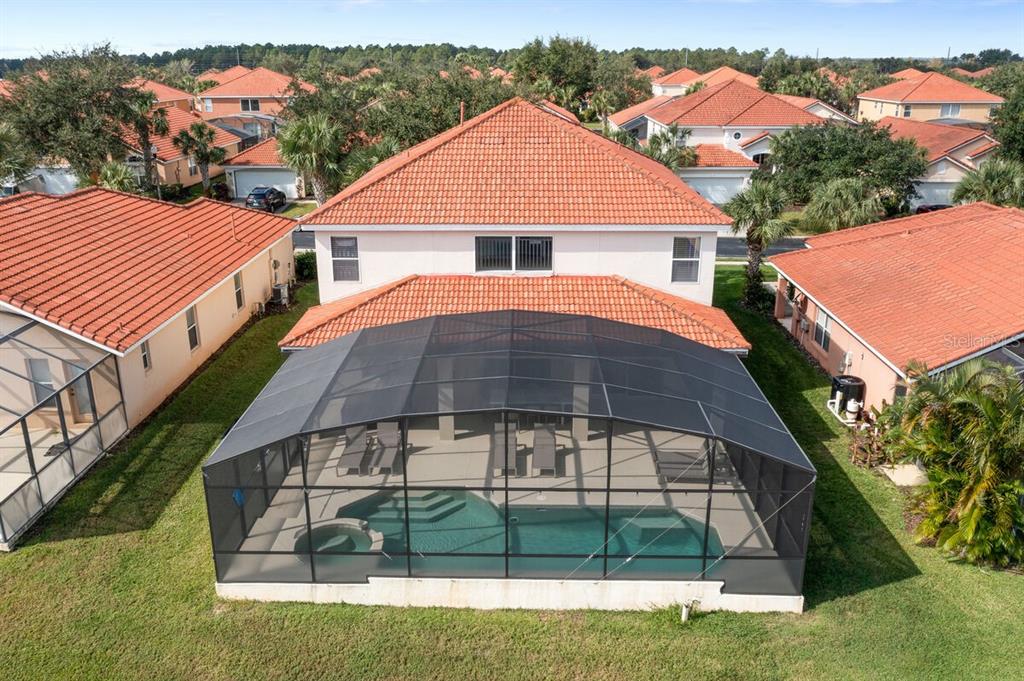 An aerial view of a two-story house with a screened-in pool and patio area — 166 CARRERA AVENUE, DAVENPORT, FL