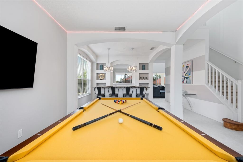 A game room features a yellow pool table, a bar area, and a staircase — 166 CARRERA AVENUE, DAVENPORT, FL