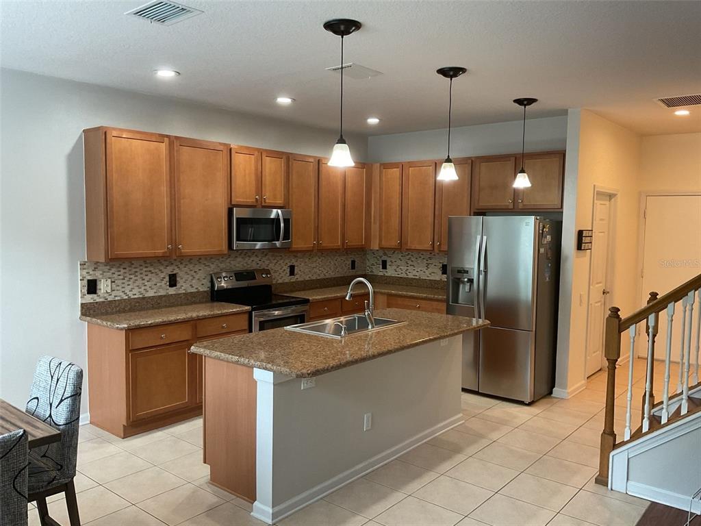 A kitchen features wood cabinets, granite countertops, a center island, and stainless steel appliances — 14024 WAKE ROBIN DRIVE, BROOKSVILLE, FL