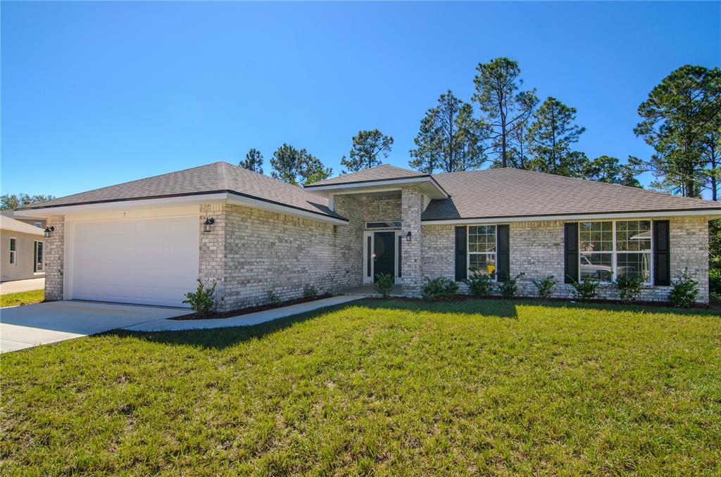 A single-story brick house features a two-car garage, black shutters, and a front entryway — 79 SLUMBER MEADOW TRAIL, PALM COAST, FL