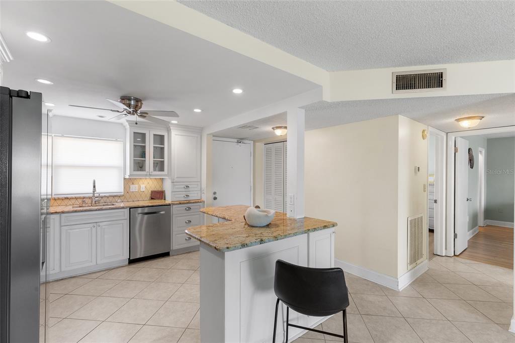 A kitchen with white cabinets, granite countertops, stainless steel appliances, and tile flooring — 4775 COVE CIRCLE UNIT 202, ST PETERSBURG, FL