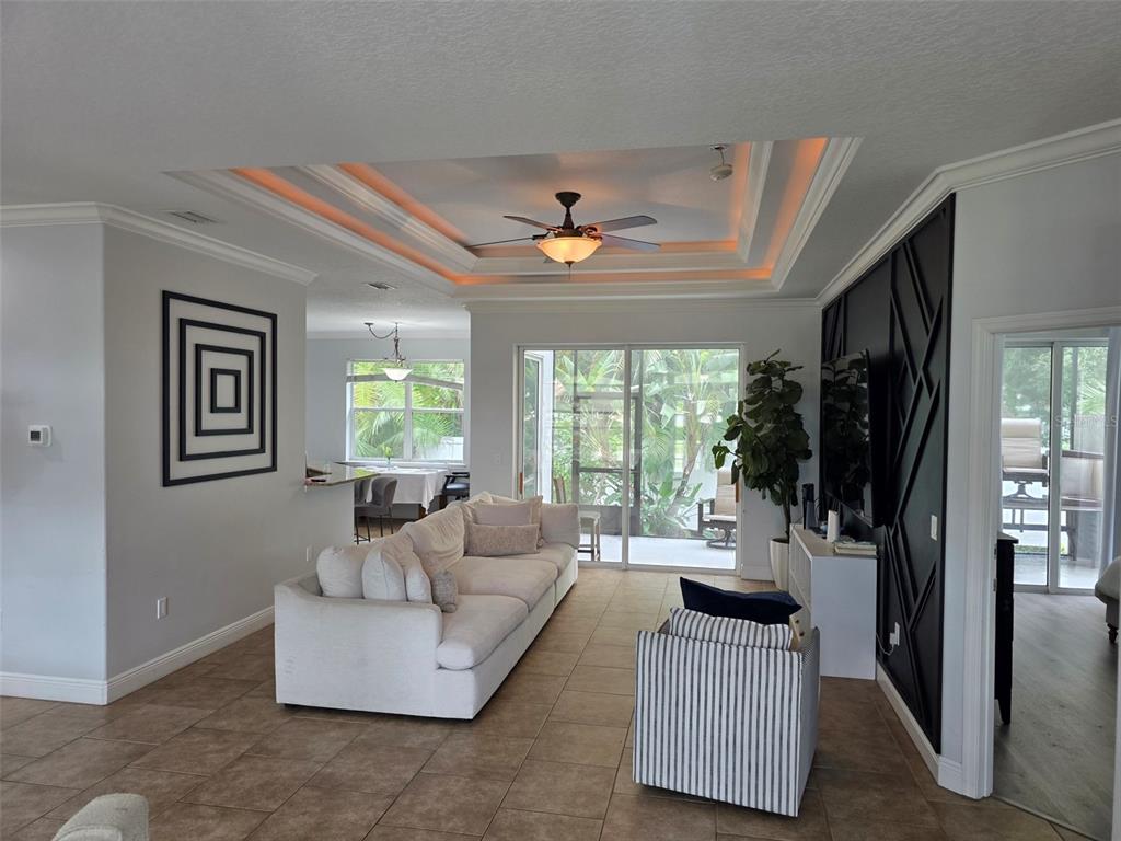 A living room features a tray ceiling, a large white sofa, and a black accent wall — 4644 SAWYER ROAD, SARASOTA, FL
