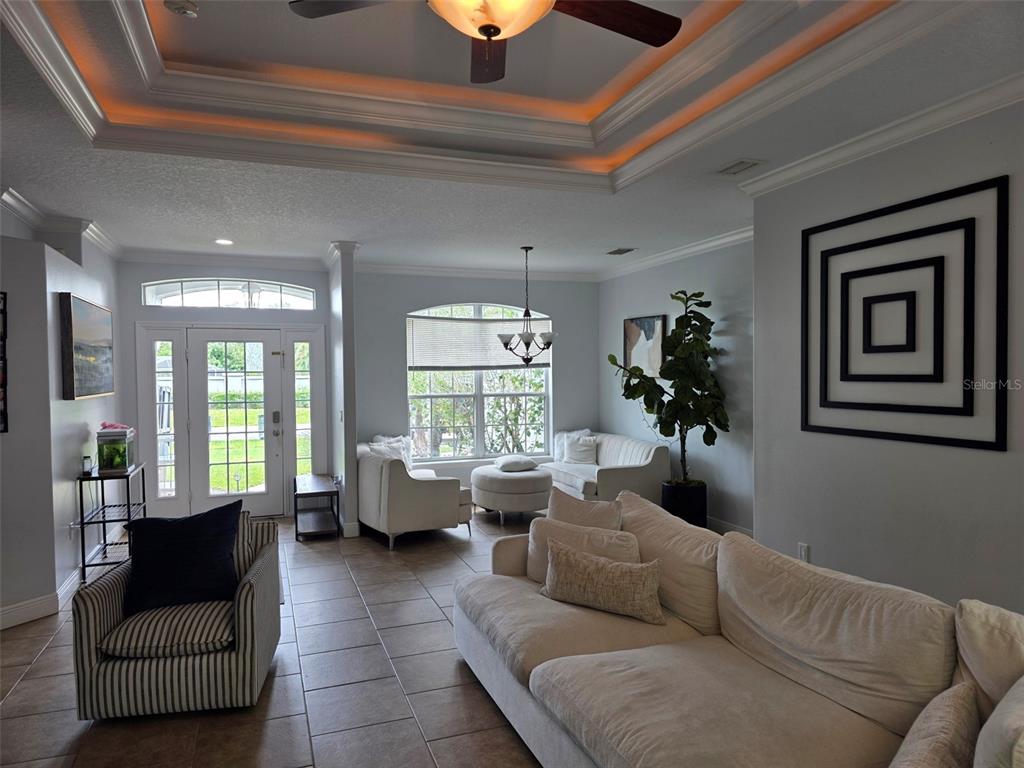 A living room features tile floors, a tray ceiling with recessed lighting, and neutral furniture — 4644 SAWYER ROAD, SARASOTA, FL