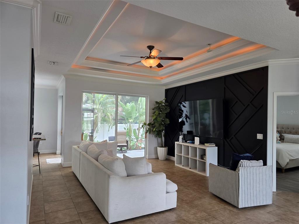 A living room features a tray ceiling, a black accent wall, and a white sofa — 4644 SAWYER ROAD, SARASOTA, FL