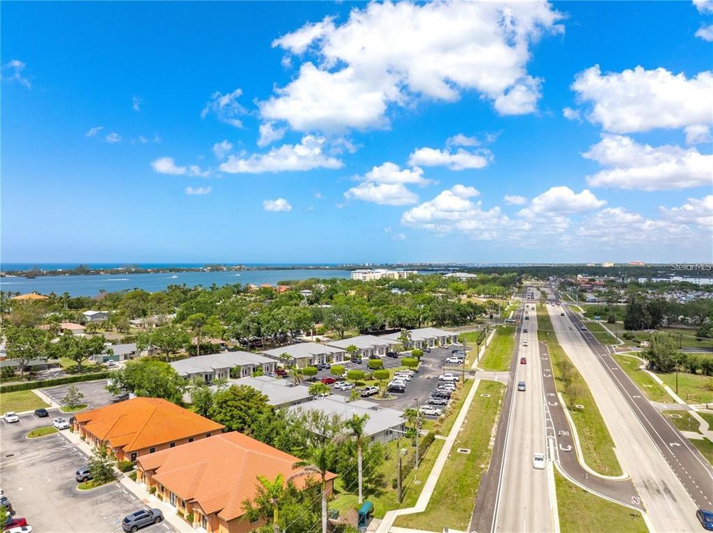 An aerial view shows a commercial complex with orange-tiled roofs near a road and water — 436 S TAMIAMI TRAIL UNIT C4, OSPREY, FL