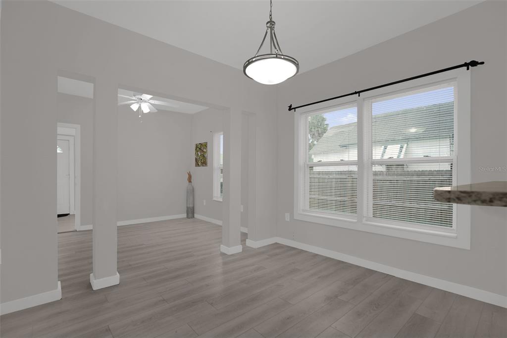 A dining area with light wood floors, a pendant light, and windows with blinds — 1416 6TH STREET, ST CLOUD, FL