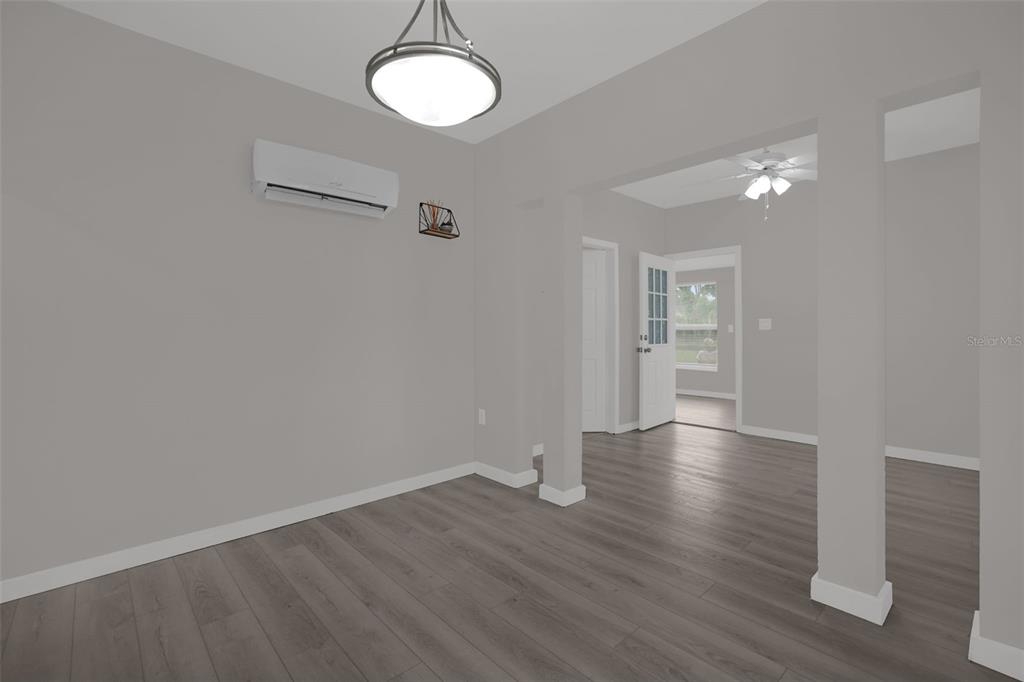 A room with gray walls, wood-look flooring, a ceiling light, and a wall-mounted air conditioner — 1416 6TH STREET, ST CLOUD, FL