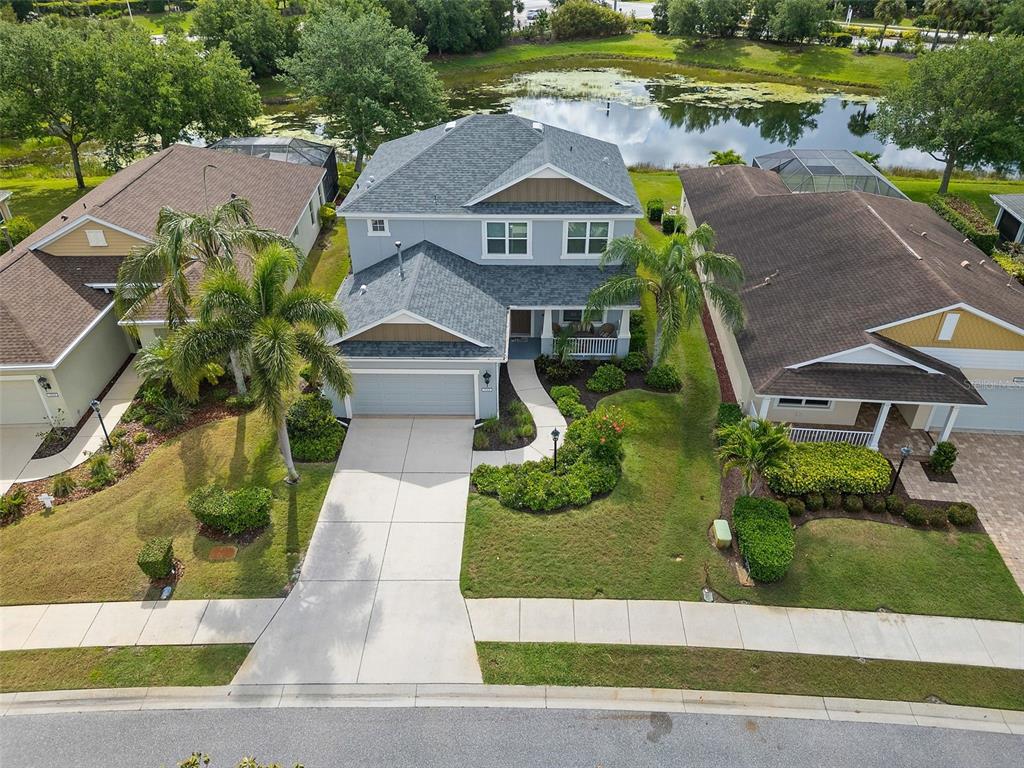 An aerial view shows a two-story gray house with a garage and a backyard pond — 11904 FOREST PARK CIRCLE, BRADENTON, FL