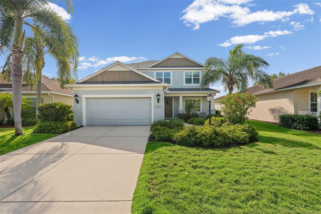 A two-story suburban house with a concrete driveway, a two-car garage, and palm trees — 11904 FOREST PARK CIRCLE, BRADENTON, FL