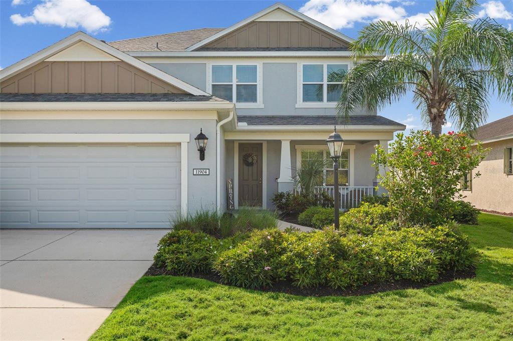 A two-story suburban house features a gray exterior, a two-car garage, and front landscaping — 11904 FOREST PARK CIRCLE, BRADENTON, FL