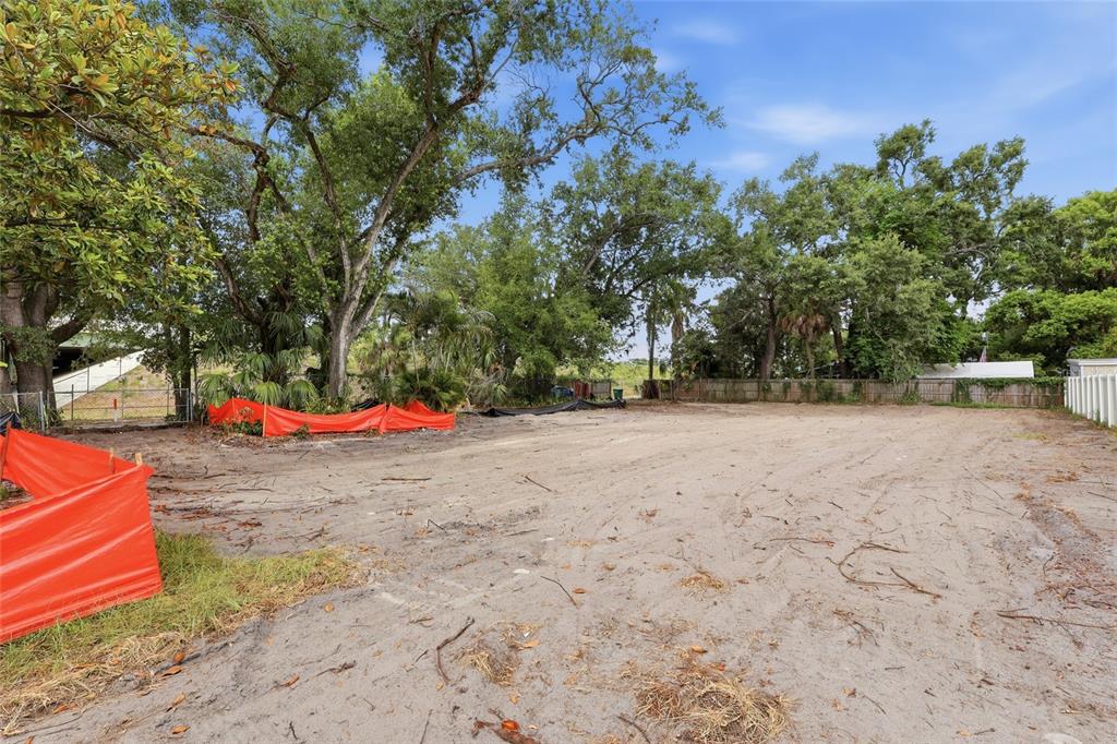 A cleared, sandy vacant lot is surrounded by mature trees and orange construction fencing — 6201 E KING STREET, TAMPA, FL